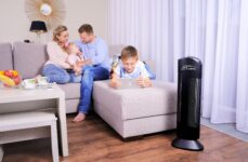 Purificatore d'aria Ionic-CARE in soggiorno, v pozadí rodina relaxující na světlé pohovce u okna, colore nero